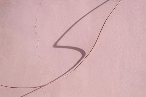 Wire and shadow from it against the background of a wall with a crack Stock Photos