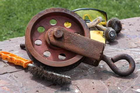 Wire brush cleaning old rusty steel hoist reel 스톡 사진