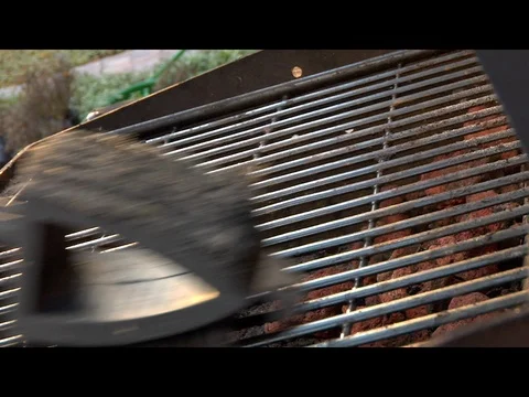 Wire brush scrubbing cleaning grill grates on dirty barbecue B Stock Footage 125489536