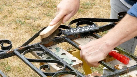 Wire brush in use on a rusty gate. Video stock 92016990