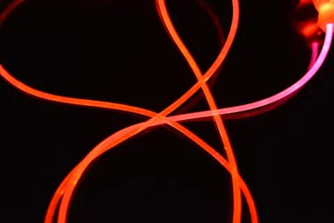 Wire, cable, polyethylene tubes, rods with red, orange, yellow, pink light. Stock Photos