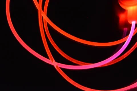 Wire, cable, polyethylene tubes, rods with red, orange, yellow, pink light. Stock Photos