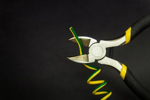 Wire cutters and wire closeup on black background. Stock Photos
