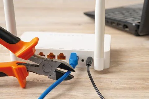 Wire cutters ready to cut the network cable connected to wi-fi router. Stock Photos