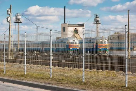 Wire fence restricting access to train depot with standing trains out of focu Stock Photos