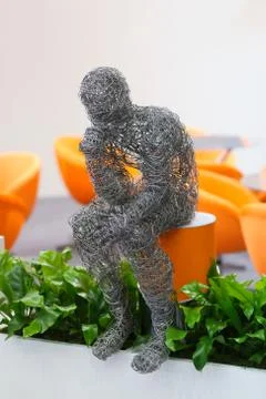 Wire figure of sitting man, grass and orange Stock Photos