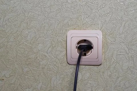 A wire with a plug from an electrical appliance is inserted into an outlet Stock Photos