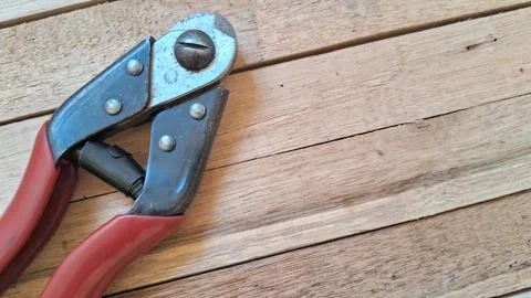 Wire rope cutter with red handles. Heavy duty steel cable cutting tool on wooden Stock Photos