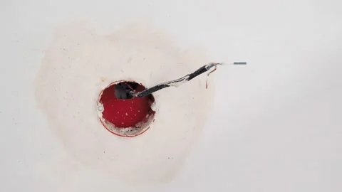The wire is in the wall after repair. A bare electrical wire sticks out of the Stock Footage 233922204