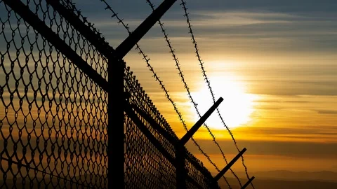 Wired Fence with Barbed Wire and Mesh Steel Wall with Sunset in Background 動画素材 102644522