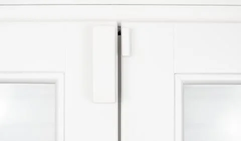 Wireless alarm sensor for window and door on white wooden sash Stock Photos