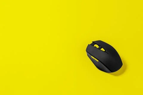 Wireless black computer mouse on yellow background with copy space Stock Photos