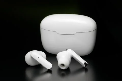 Wireless bluetooth headphones in white case isolated on black background. Stock Photos