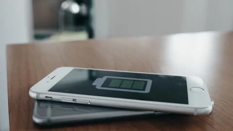 Wireless Charging, A cell phone is sitting on a table with a battery indicato Stock Footage 313550905