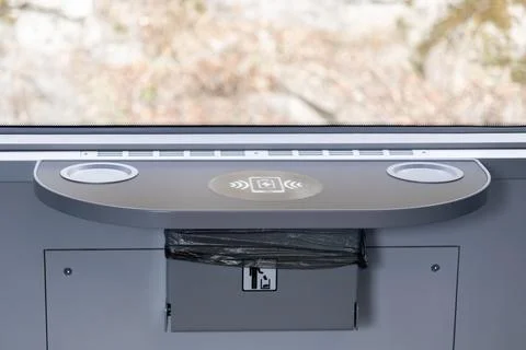 A wireless charging pad sits on a modern passenger train seat tray table to 스톡 사진