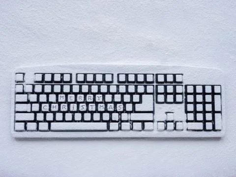 Wireless computer keyboard covered with white snow with text merry christmas on 스톡 사진