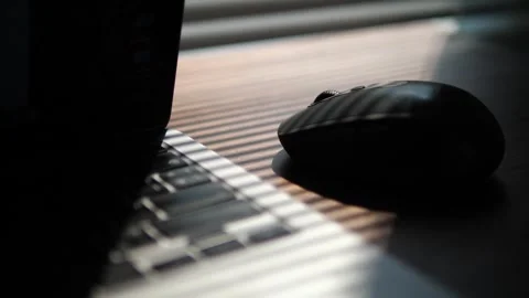Wireless computer mouse and laptop keyboard under dramatic window blind shadows Stock-Footage 332421696
