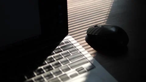 Wireless computer mouse and laptop keyboard under dramatic window blind shadows 스톡 동영상 332421697