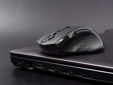 Wireless computer mouse on closed laptop with dark background Stockfoto's