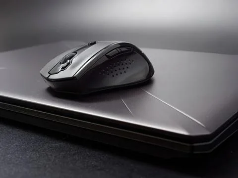 Wireless computer mouse on closed laptop with dark background Stockfoto's