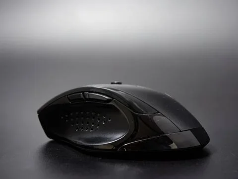 Wireless computer mouse on a dark surface in a modern setting Stock Photos