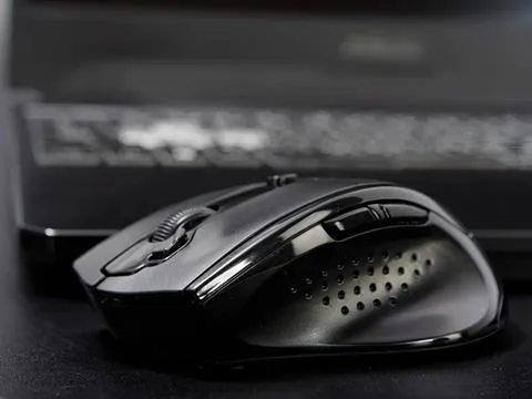 Wireless computer mouse on desk with keyboard in background Stockfoto's