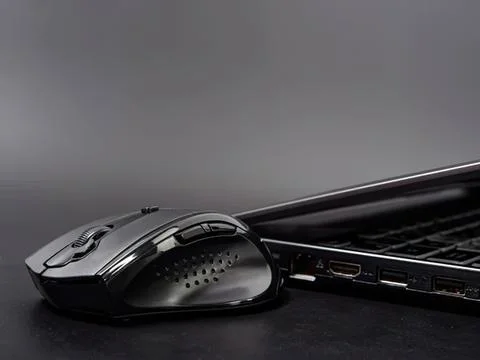 Wireless computer mouse next to a laptop on desk Stock Photos