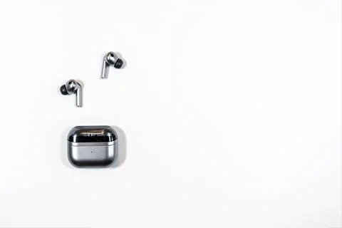 Wireless earbuds and charging case placed on a clean white surface in a Stock Photos