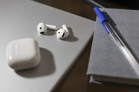 Wireless earbuds and charging case on a modern desk Stock Photos