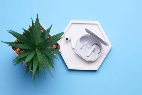 Wireless earbuds with charging case on a blue surface Stock Photos