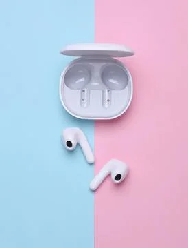 Wireless earbuds with charging case on pastel background Stock Photos