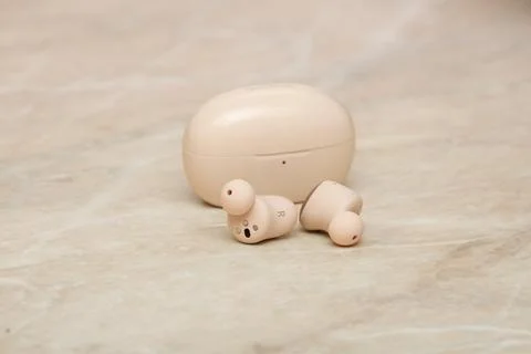 Wireless earbuds in-ear with charging box on the table close-up. Stock Photos