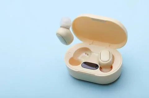 Wireless earbuds in open charging case on blue background Stock Photos