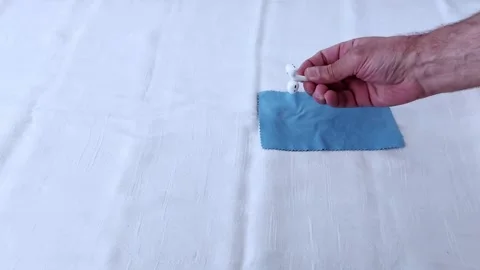 Wireless Earbuds Resting on Blue Fabric- Minimalist Moment Stock-Footage 311795533