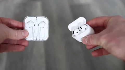 Wireless earbuds vs wired headphones closeup comparison hands holding both optio Stock Footage 306007798