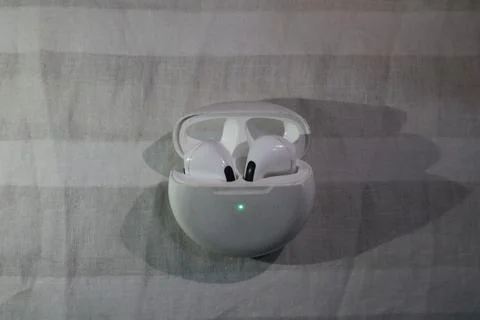 Wireless earbuds in white charging case on gray fabric background with gree.. Foto stock