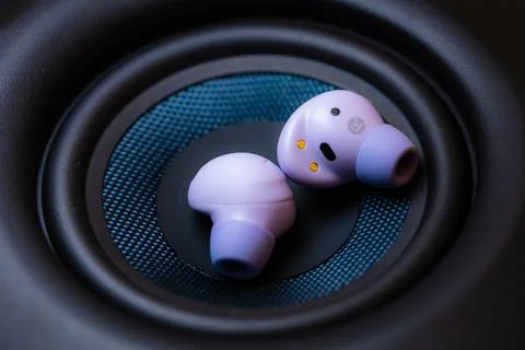 Wireless earpone buds on speakers background Stock Photos