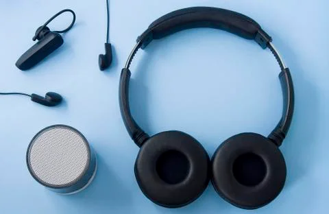 Wireless headset, wired headset, speaker isolated on pastel blue background.  Stock Photos
