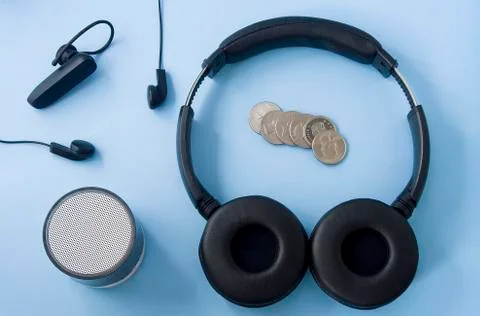 Wireless headset, wired headset, speaker and coins isolated on pastel blue ba Stock Photos