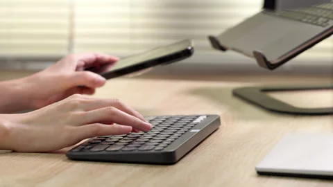 Wireless keyboard and smartphone, hands typing in home office. Stock Footage 316657021