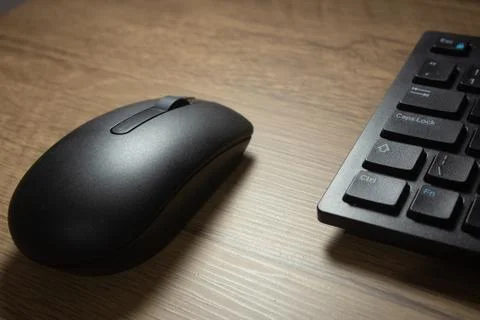 Wireless mouse and keyboard set on top of a wooden office desk, on a workstat Stock Photos