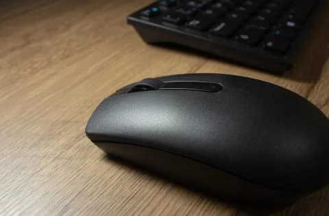 Wireless mouse and keyboard set on top of a wooden office desk, on a workstat Stock Photos