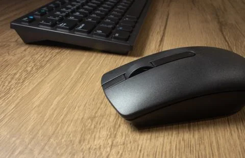 Wireless mouse and keyboard set on top of a wooden office desk, on a workstat Foto stock