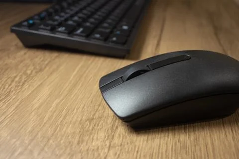 Wireless mouse and keyboard set on top of a wooden office desk, on a workstat Stock Photos
