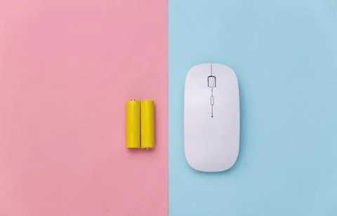 Wireless pc mouse and two batteries on a blue-pink pastel background. Top vie Stock Photos