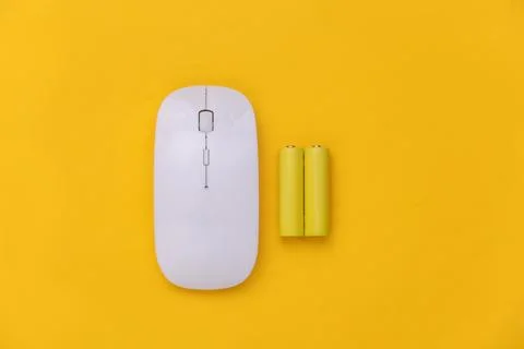 Wireless pc mouse and two batteries on yellow background. Top view Stockfoto's