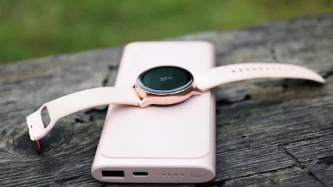 Wireless power bank lying on the bench and charging the smartwatch. Stock-Footage 157875924