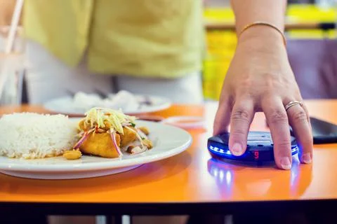 Wireless queue caller machine in hand of customer with food. Stock Photos
