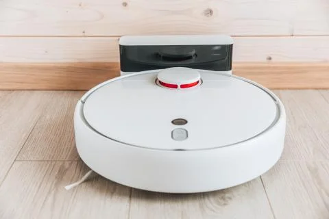 Wireless robot vacuum cleaner return to charging at dock in clean wooden floo Stock Photos
