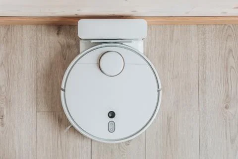 Wireless robot vacuum cleaner return to charging at dock in clean wooden floo Stock Photos
